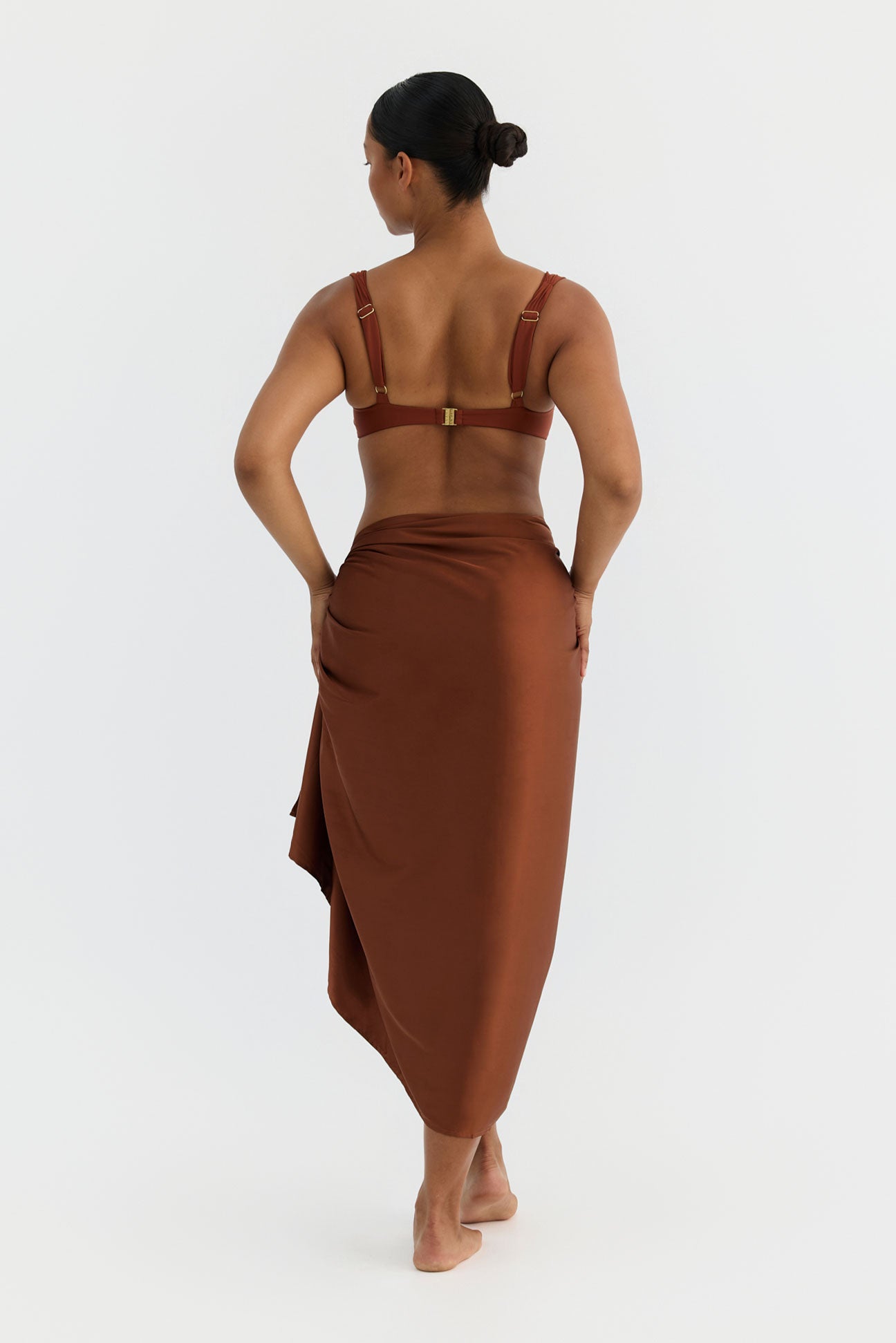 Woman wearing a bronze sarong with bikini set on a white background