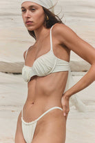 Woman wearing a white bikini set with a neutral background