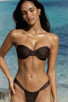 Woman wearing a brown bikini set with a clear blue ocean background
