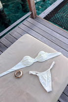 White bikini set on a wooden deck with a ring nearby