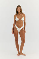 Woman wearing white triangle bikini on a white background.