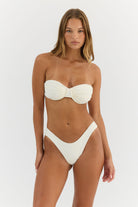 Woman wearing a white bikini against a white background