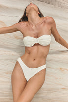 Person wearing a white bikini against a neutral background