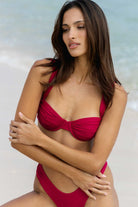 Woman wearing a magenta bikini against a light background