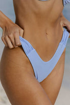 Light blue bikini bottom worn by a person on a beach.