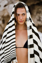 Woman wrapped in a black and white striped towel against a rocky background