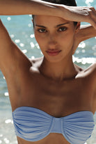 Woman wearing a light blue bikini top with a blurred water background